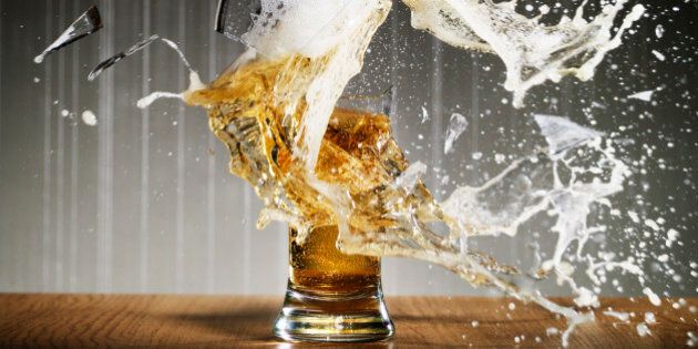 Glass of beer shattering on table surface