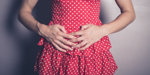 A young woman is touching her stomach because she has a belly ache