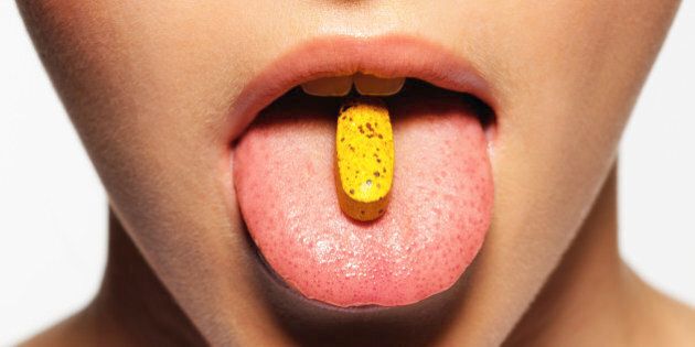 Young woman with pill on tongue, close-up