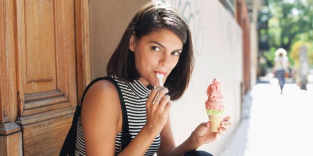 young woman sitting on doorstep, eating ice cream