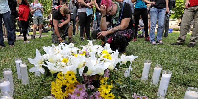 People pay their respects at a vigil where 20 candles were burned for the 19 people injured and one killed when a car plowed into a crowd of counter-protesters at the