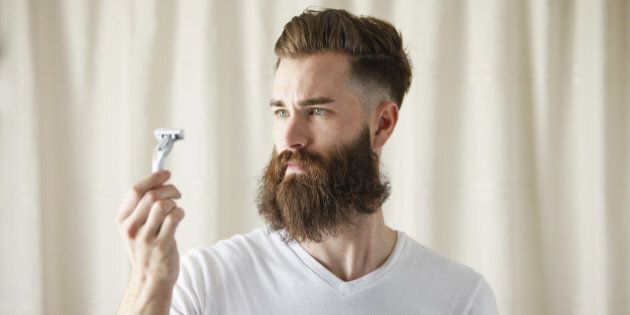 Bearded Caucasian man examining razor