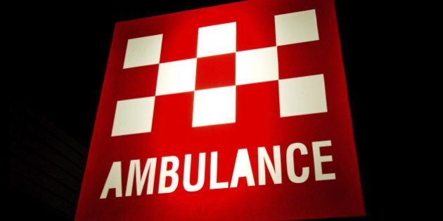 Australian Ambulance sign illuminated at night. Background is pure black and easily extendable.