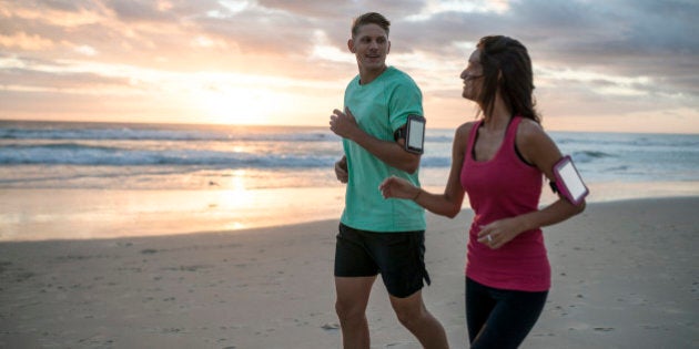 Young couple running on the beach at early morning hours.