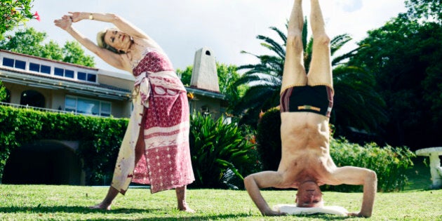 Senior couple performing yoga on lawn, man doing headstand