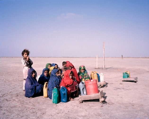 Children pause during their journey to collect water, huddling together against the wind in southern Sindh. Floods gripped the country in 2010 and 2011, leaving behind only barren land. Agriculture in the region was devastated.