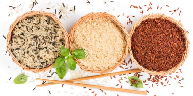 Top view of different rice types in a baskets decorated with basil and chopsticks isolated on white background