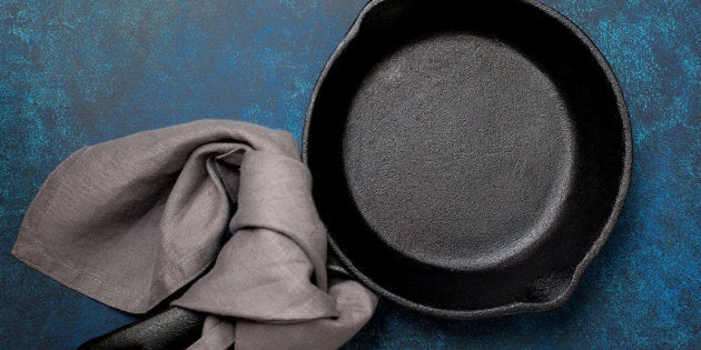 Empty cast-iron frying pan on a blue background (top view)