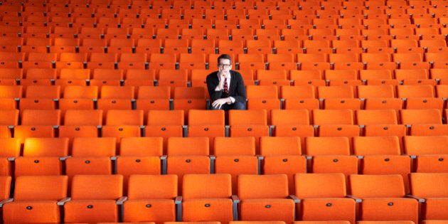 A curious man sitting in an empty auditorium