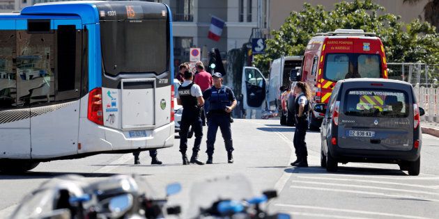 French police secure the area where one person was killed and another injured after a car crashed into two bus shelters.