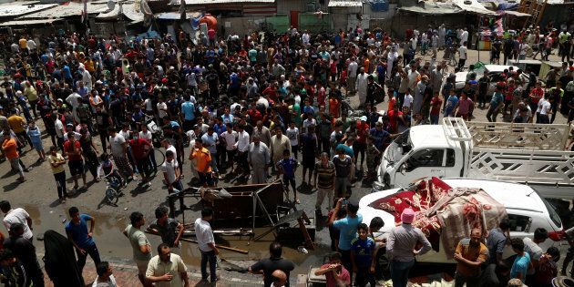 People gather at the scene of a car bomb attack in Baghdad's mainly Shi'ite district of Sadr City, Iraq.