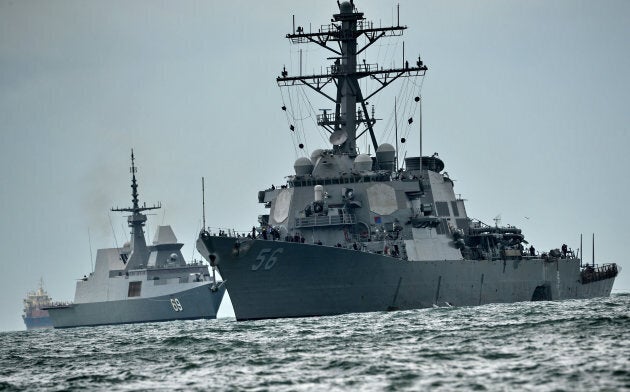 The guided-missile destroyer USS John S. McCain (R), with a hole on its portside.