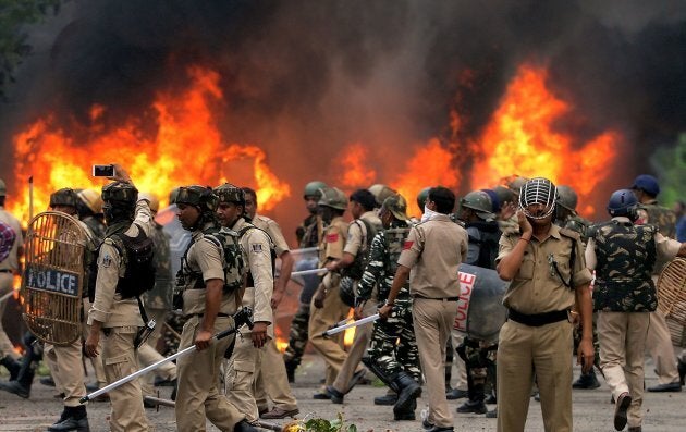 Indian security forces walk next to burning vehicles set alight by rioting followers of a religious leader convicted of rape in Panchkula on August 25, 2017.