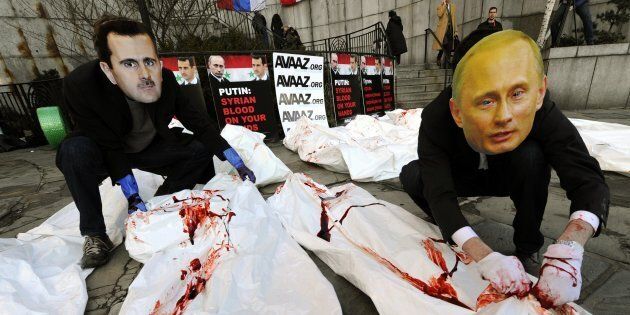 Actors from Avaaz wearing giant masks of Bashar al-Assad and Vladimir Putin dump dozens of bloodied body bags outside the UN Security Council building January 24,2012 as members of the UN Security Council meet in New York to discuss the Syria crisis, Avaaz will deliver a petition signed by more than 620,000 people worldwide calling for the UN to refer President Bashar al-Assad to the ICC for crimes against humanity. AFP PHOTO / TIMOTHY A. CLARY (Photo credit should read TIMOTHY A. CLARY/AFP/Getty Images)