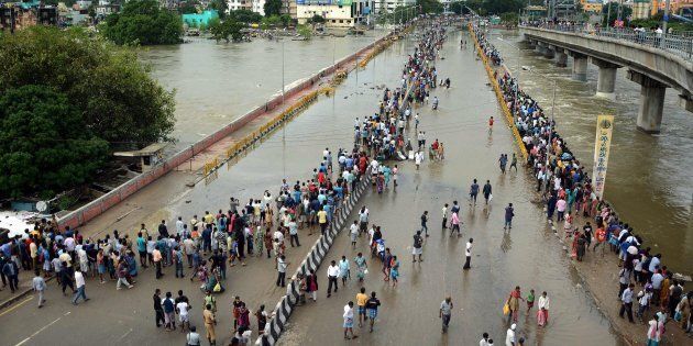 This general view shows Indian residents as they look at floodwaters on a major highway in Chennai on December 3, 2015. Thousands of rescuers raced to evacuate residents from deadly flooding, as India's Prime Minister Narendra Modi went to the southern state of Tamil Nadu to survey the devastation. More than 40,000 people have been rescued in recent days after record rains lashed the coastal state, worsening weeks of flooding that has killed 269 people AFP PHOTO/STR / AFP / STRDEL (Photo credit should read STRDEL/AFP/Getty Images)