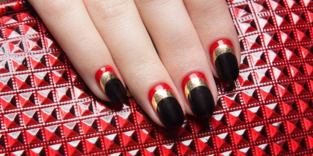 Beautiful women's manicure with black, red, gold polish on the nails. Picture taken in the studio. Close-up.