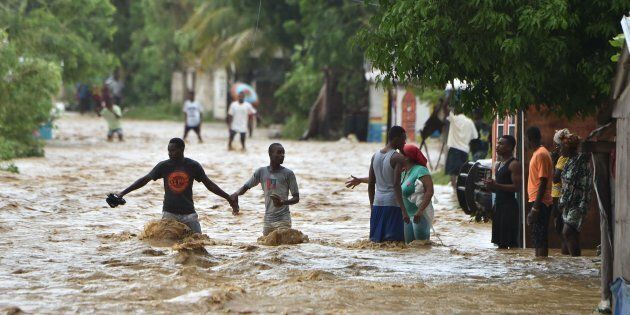 People try to cross the overflowing La Rouyonne river in the commune of Leogane, south of Port-au-Prince, Haiti, on Oct. 5.