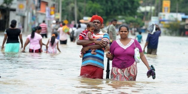 TOPSHOT - A Sri Lankan couple with their child make their way through floodwaters in the suburb of Kaduwela in capital Colombo on May 17, 2016. Emergency workers in Sri Lanka on May 17 found the bodies of a woman and two children killed in a landslide, taking the toll from two days of heavy rain to 11, with thousands more forced to flee their homes. / AFP / LAKRUWAN WANNIARACHCHI (Photo credit should read LAKRUWAN WANNIARACHCHI/AFP/Getty Images)