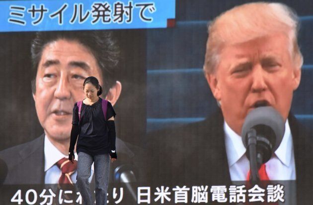 A woman walks in front of a huge screen displaying Japanese Prime Minister Shinzo Abe and U.S. President Donald Trump in Tokyo on August 29.
