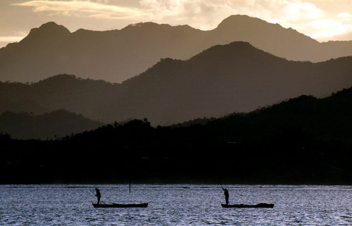 Fijian fishermen stand in their boats in Suva.