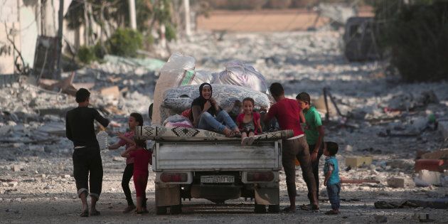 Children sit on a pick-up truck loaded with belongings along a damaged street in Manbij, Aleppo Governorate, Syria, August 16, 2016. REUTERS/Rodi Said