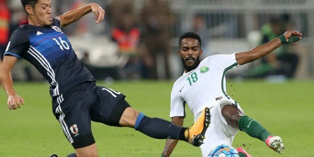 Saudi Arabia's Nawaf Alabid fights for the ball against Japan's Hotaru Yamaguchi.