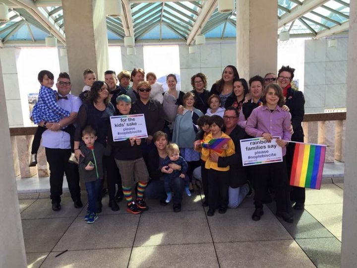 The Rainbow Families group in Canberra on Tuesday; Callum (blue hair, holding sign), Sadie (grey shawl, middle), Annette (glasses, behind Sadie), Samantha (short hair and vest on right of photo), Rafi (striped shirt, holding sign) and Felicity (behind Rafi, glasses and dark jacket)