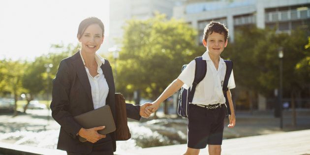 Smiling businesswoman walking with son outdoors