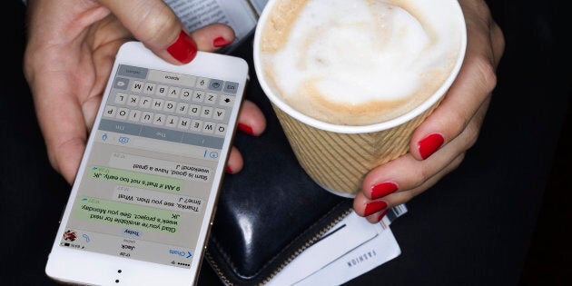 Female holding take away coffee, texting, close up