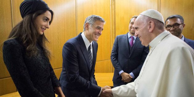 George Clooney, with his wife, Amal, shakes the hand of Pope Francis during Sunday's meeting.