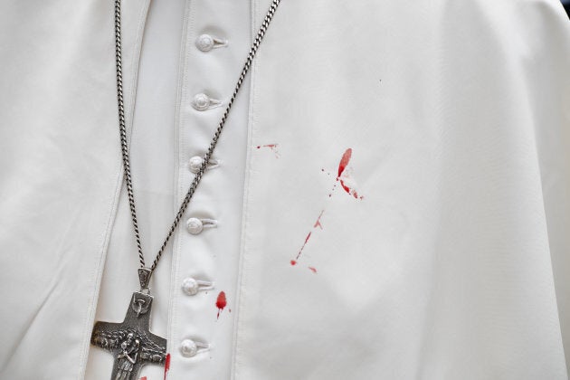 A few droplets of blood stain Pope Francis' white tunic.