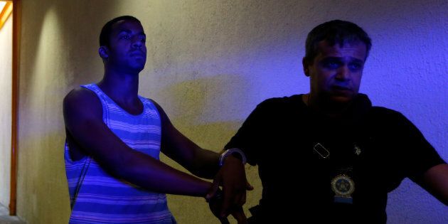Rai de Souza (L), 22, suspected of being involved in the gang rape of a teenage girl, with a video of the assault circulated widely on social media, is escorted at the Police Station for crimes against minors in Rio de Janeiro, Brazil, May 30, 2016. REUTERS/Ricardo Moraes
