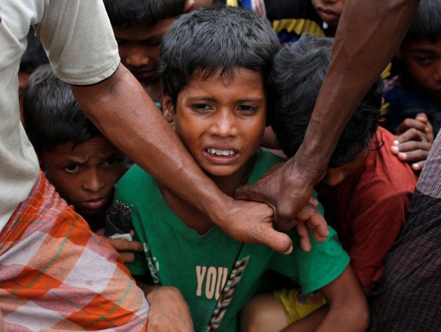Rohingya refugee children are stopped by volunteers as they jostle to receive food distributed by local organizations in Kutupalong, Bangladesh, September 9, 2017.