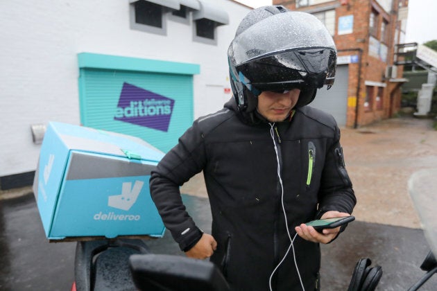 A Deliveroo delivery driver looks at an app on his smartphone