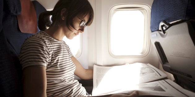 Woman reading newspaper in aeroplane, close-up