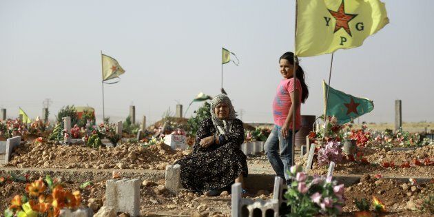 A Syrian Kurdish woman sits next to the grave of a relative during the funeral of fighters, who died during an assault launched by Arab and Kurdish forces against Islamic State (IS) group fighters in the town of Manbij, in the Syrian Kurdish town of Kobane on June 4, 2016. Arab and Kurdish fighters backed by Washington have launched an assault on the strategic Manbij pocket further up the Euphrates on the Turkish border, regarded as a key entry point for foreign jihadists.The Syrian Democratic Forces's offensive against the Manbij pocket is aimed at seizing the last stretch of border still under IS control and denying the jihadists any opportunity to smuggle in recruits and funds. / AFP / Delil Souleiman (Photo credit should read DELIL SOULEIMAN/AFP/Getty Images)