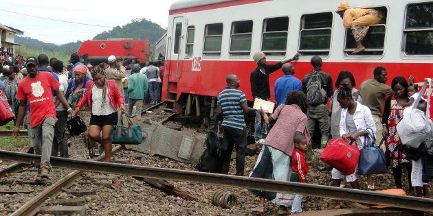 TOPSHOT - A passenger escapes a train car using a window as others leave from the site of a train derailment in Eseka on October 21, 2016. Fifty-three were killed and over 300 injured when a packed Cameroon passenger train derailed on October 21 while travelling between the capital Yaounde and the economic hub Douala, state broadcaster Crtv said. The train, crammed with people due to road traffic disruption between the two cities, left the tracks just before reaching the central city of Eseka, Transport minister Edgar Alain Mebe Ngo'o said earlier. / AFP / STRINGER (Photo credit should read STRINGER/AFP/Getty Images)