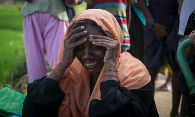 A woman who lost her husband and two sons to military violence in Myanmar cries on the side of the road.
