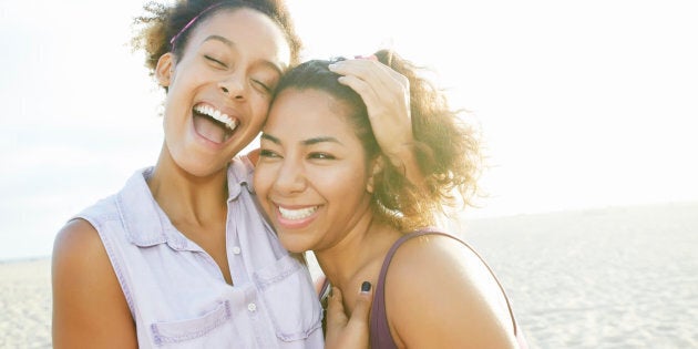 Smiling friends hugging at beach