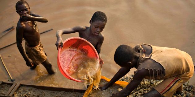 Boys pan for gold on a riverside at Iga Barriere in eastern Congo.