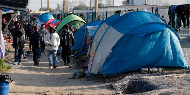 Migrants walk in an alley near tents and makeshift shelters on the eve of the evacuation and dismantlement of the camp called the