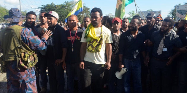 A Papua New Guinea police officer (L) prevents students from marching from the University of Papua New Guinea in Port Moresby, Papua New Guinea, June 8, 2016.