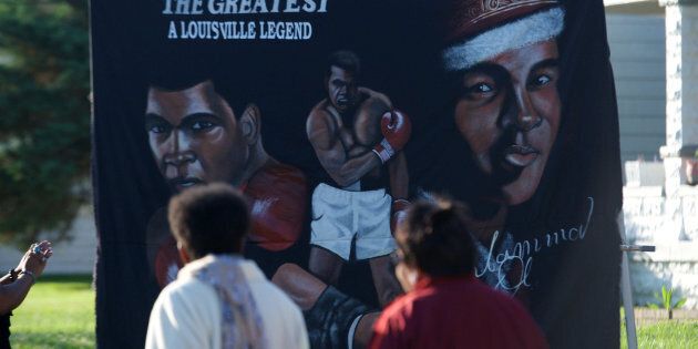 Jun 10, 2016; Louisville, KY, USA; People walk in front of a banner in front of the boyhood home of Muhammad Ali on Grand Avenue before the passing of the funeral processional. Mandatory Credit: Joshua Lindsey-USA TODAY Sports
