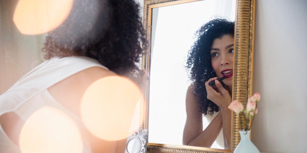 Mixed race woman applying lipstick in mirror