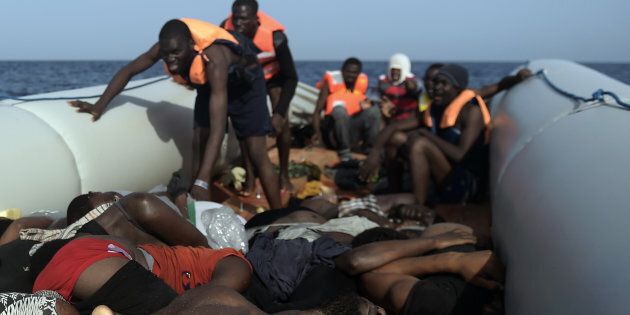 TOPSHOT - EDITORS NOTE: Graphic content / Migrants step over dead bodies while being rescued by members of Proactiva Open Arms NGO in the Mediterranean Sea, some 12 nautical miles north of Libya, on October 4, 2016.Twenty-eight Europe-bound migrants were found dead on a day of frantic rescues off Libya, including at least 22 in an overloaded wooden boat, an AFP photographer and the Italian coastguard said. / AFP / ARIS MESSINIS (Photo credit should read ARIS MESSINIS/AFP/Getty Images)