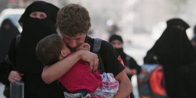 A civilian carries a child as he walks with others after they were evacuated by the Syria Democratic Forces (SDF) fighters from an Islamic State-controlled neighbourhood of Manbij, in Aleppo Governorate, Syria, August 12, 2016. The SDF has said Islamic State was using civilians as human shields. REUTERS/Rodi Said TPX IMAGES OF THE DAY