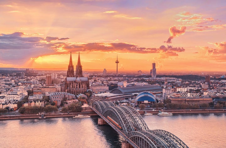 A glowing Cologne at sunset, with the Cathedral (Dom), old town, the Musical Dome and the Rhine River in view.