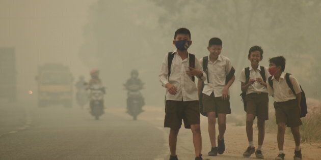 Students walk along a street as they are released from school to return home earlier due to the haze in Jambi, Indonesia's Jambi province, September 29, 2015 in this picture taken by Antara Foto. Indonesia has sent nearly 21,000 personnel to fight forest fires raging in its northern islands, the disaster management agency said on Tuesday, but smoke cloaks much of the region with pollution readings in the