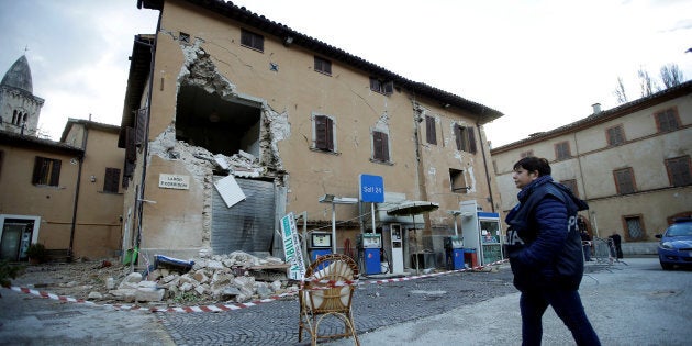 A police officer stands next to a collapsed building after an earthquake in Visso, central Italy on Thursday.