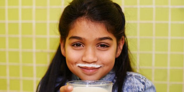 Shot of a cute little girl enjoying a milkshake at home